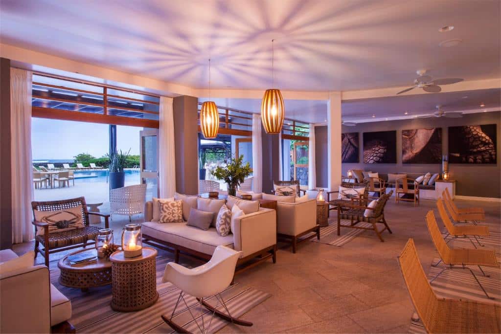 Elegant loungeområde på ett lyxhotell med bekväma sittgrupper, varm belysning och utsikt mot poolen. Finch Bay