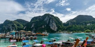 Exklusiva longtailbåtar vid turkost vatten i Phi Phi Islands med dramatiska kalkstensklippor och tropiskt landskap i bakgrunden