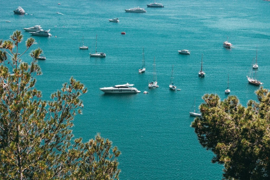 Lyxyachter och segelbåtar i turkost vatten på Franska rivieran vid Côte d’Azur