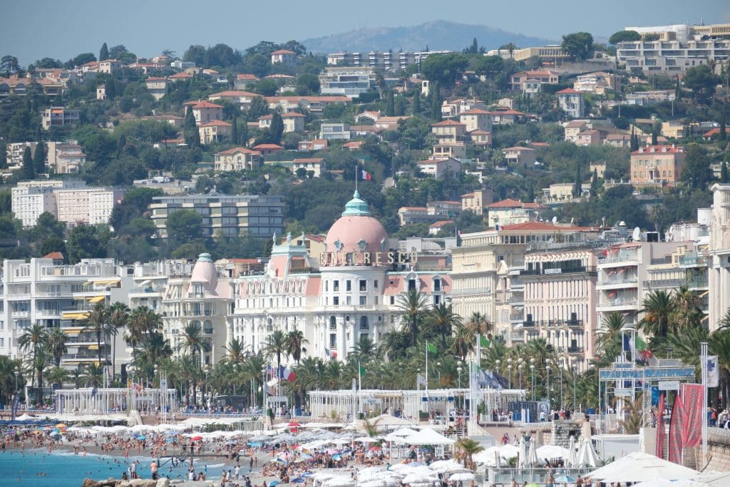 Promenade des Anglais i Nice med strandliv, palmer och Hotel Negresco på Franska rivieran
