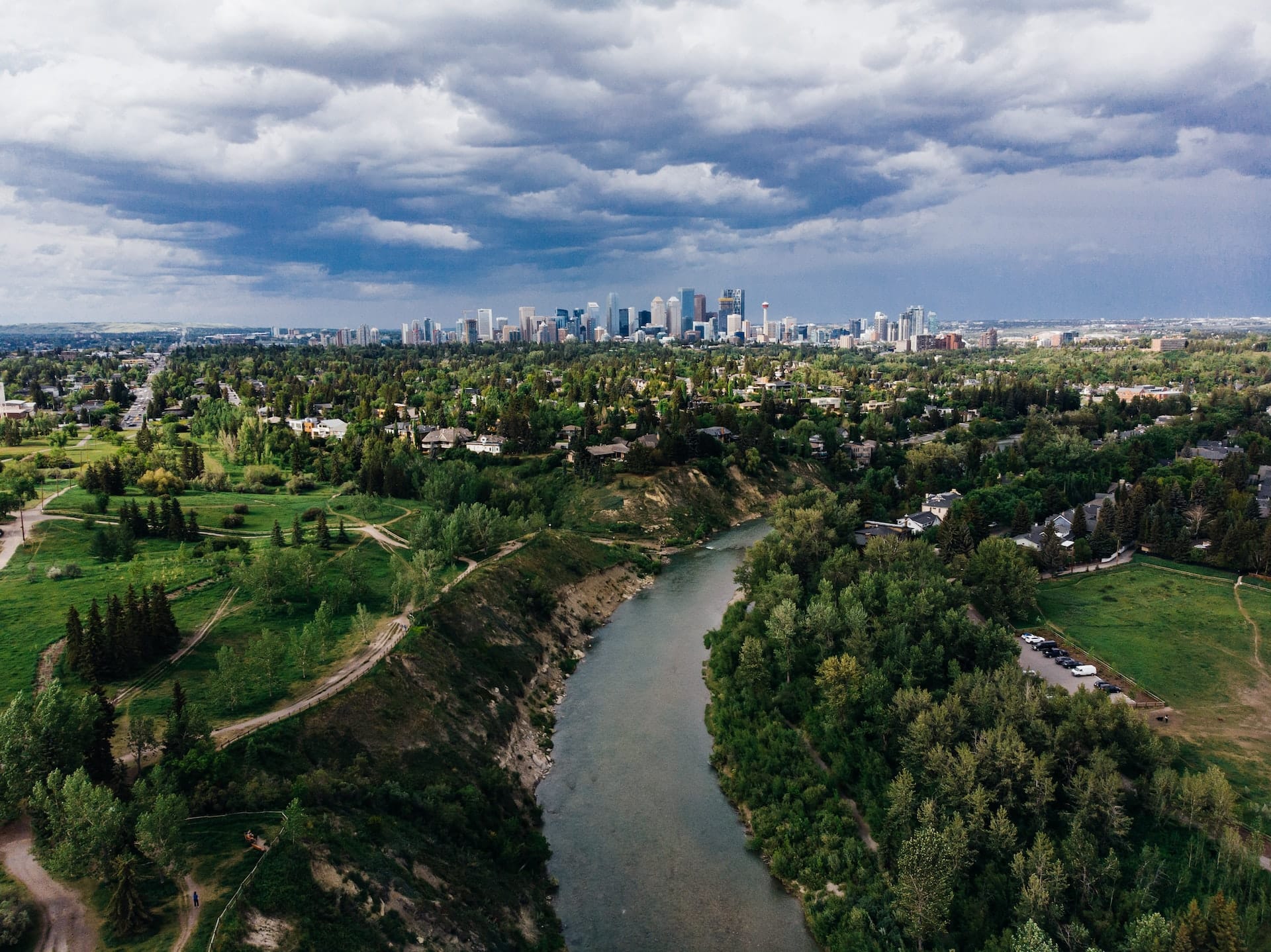 Flygfoto över Calgary med floden genom grönskande stadslandskap och skyline i bakgrunden