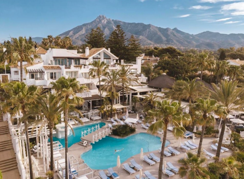 Lyxig resort i Marbella med poolområde, palmer och La Concha-berget i bakgrunden