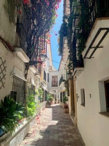 Charmig gränd i Marbellas gamla stad med vitkalkade hus, balkonger och blommande bougainvillea