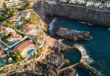 Flygfoto över exklusiva villor och naturlig havspool vid klippkusten i Los Gigantes på Teneriffa, Kanarieöarna