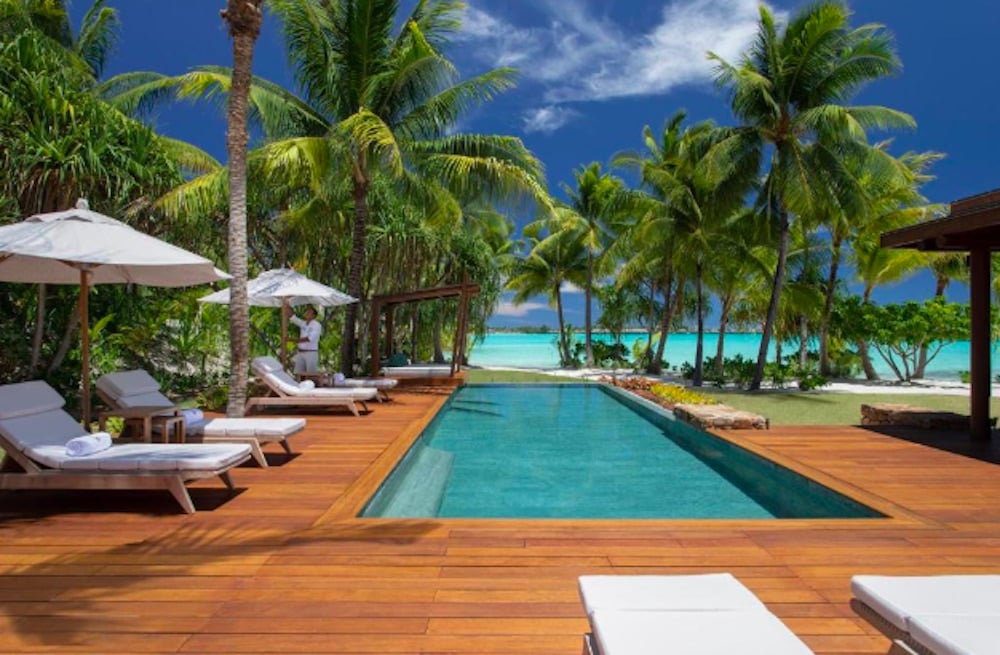 Exklusivt poolområde omgiven av palmer vid strandresort på Bora Bora