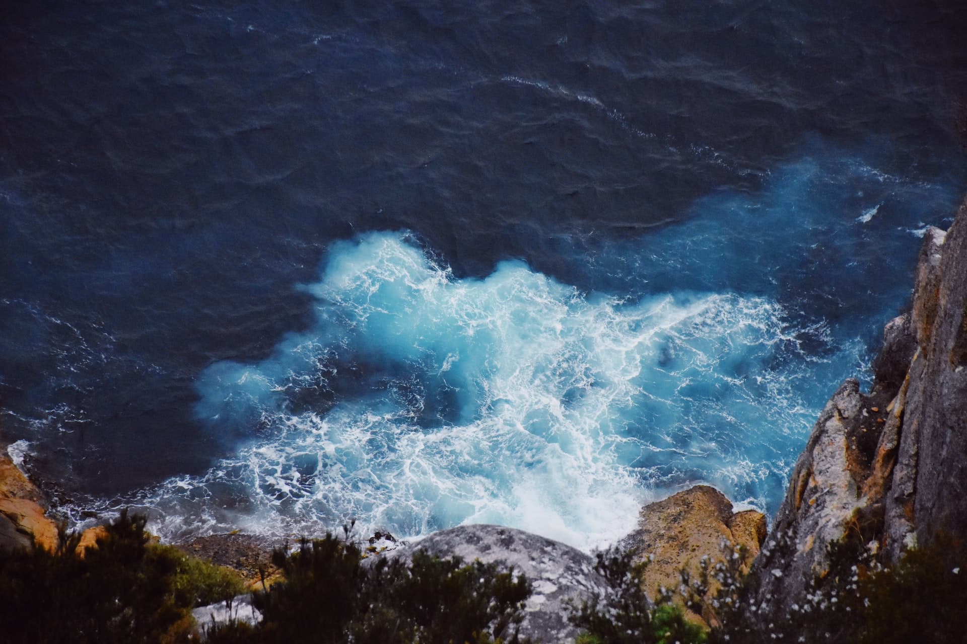 Kraftfulla vågor som slår mot klippor längs Australiens dramatiska kust, med turkosblått hav och branta klippformationer.