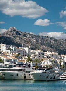 Lyxiga yachter i Marbellas marina med vita byggnader och La Concha-bergen i bakgrunden