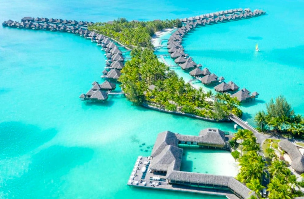 Flygvy över lyxresort på Bora Bora med vattenvillor på pålar i turkost lagunvatten
