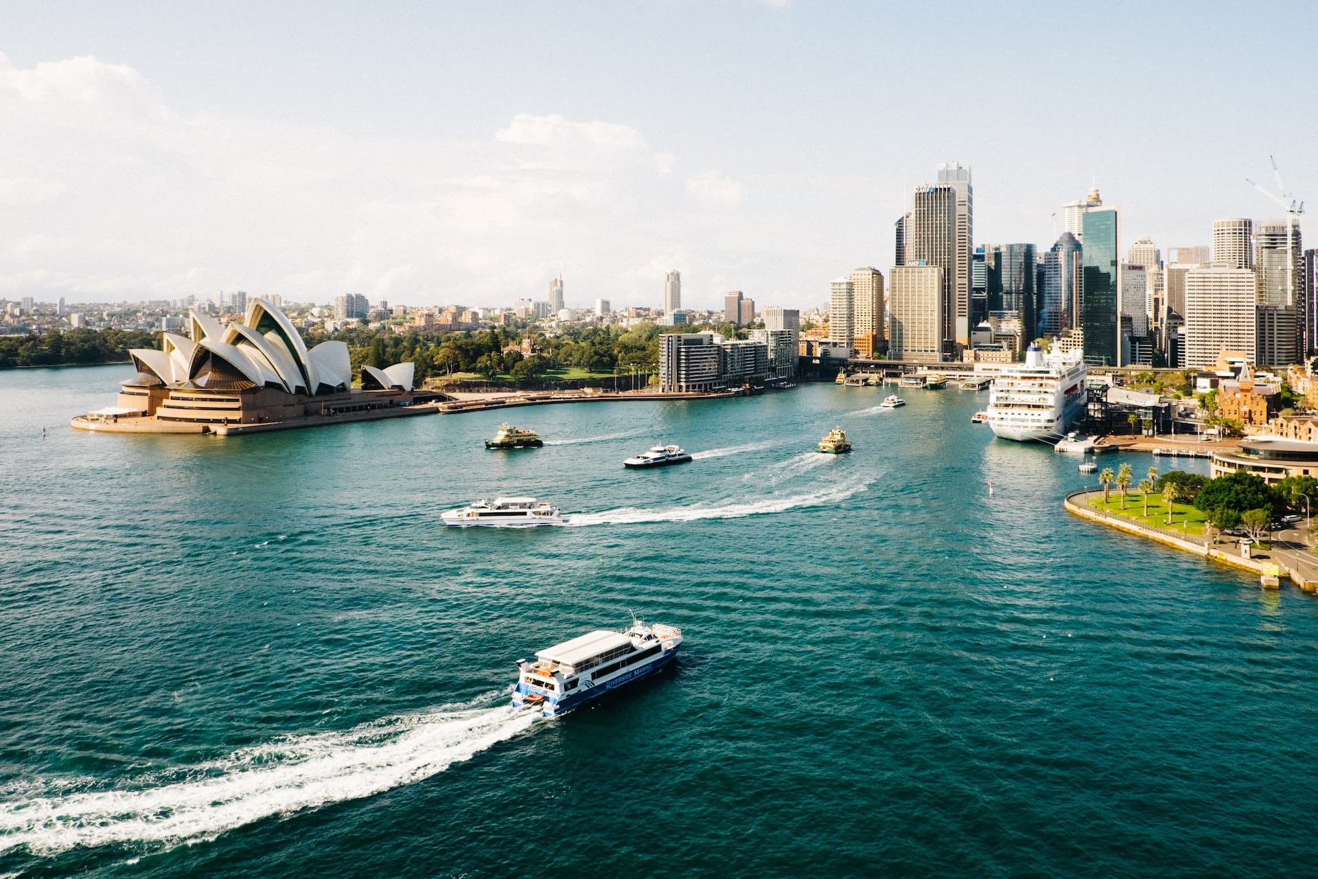Panoramautsikt över Sydney Harbour med Operahuset, stadens skyline och båtar i det turkosa vattnet – en ikonisk destination för lyxresor till Australien.