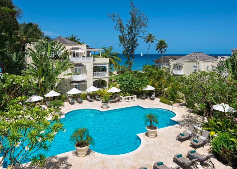 Elegant poolområde på Cobblers Cove omgivet av tropiska trädgårdar, med solstolar och lugn karibisk atmosfär.