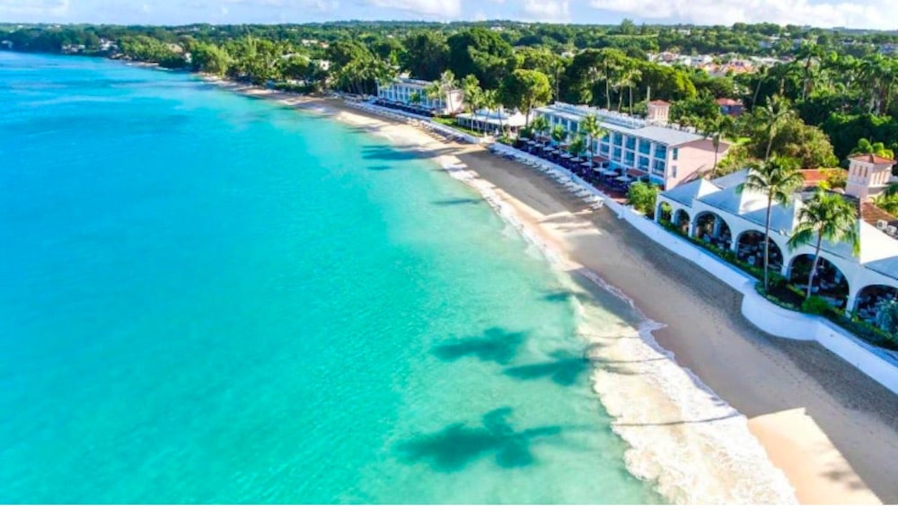 Turkost hav som möter en vit sandstrand på Barbados, med mjuka vågor och tropisk atmosfär.