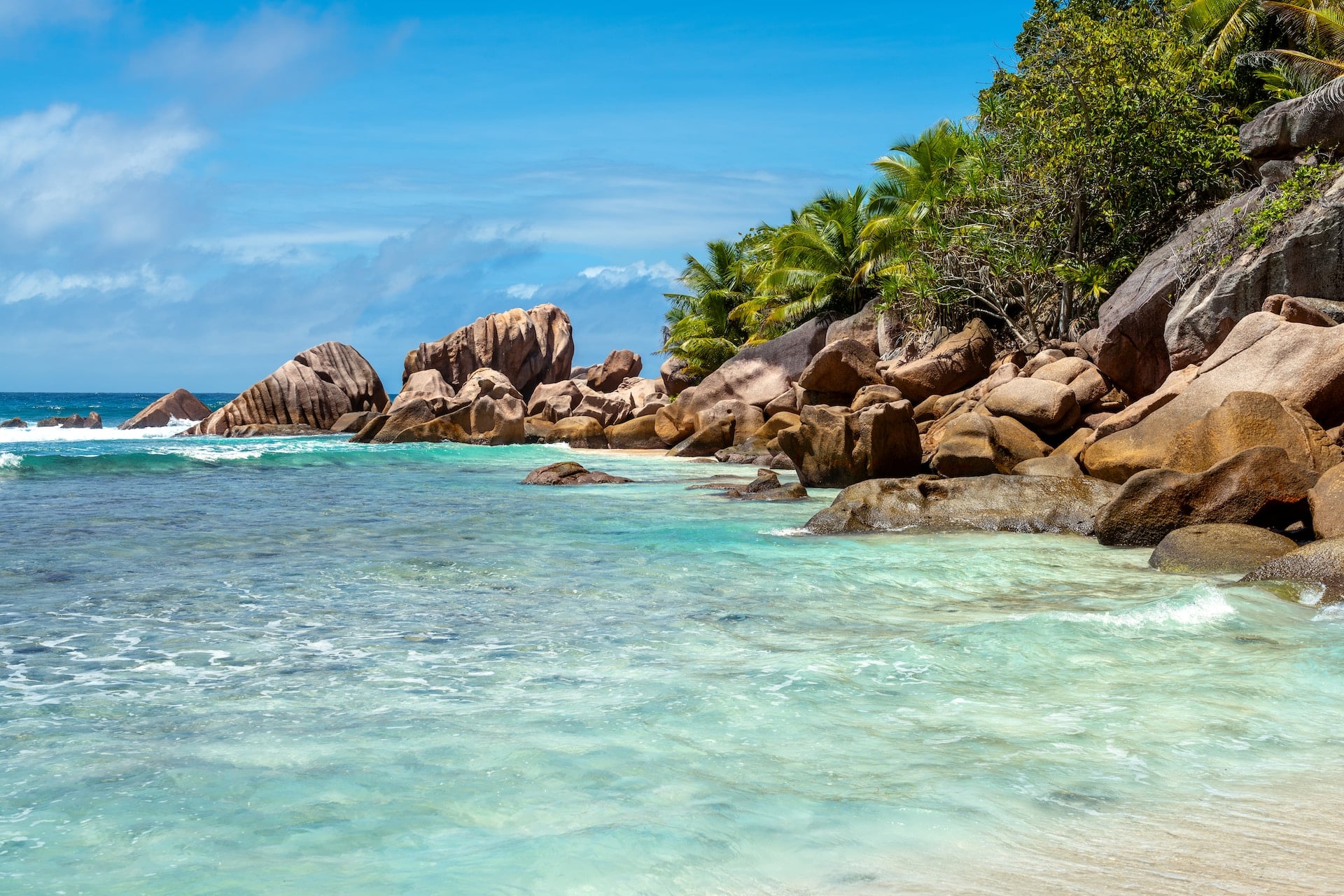 Tropisk strand på Seychellerna med granitklippor, vit sand och kristallklart turkost hav i orörd natur.