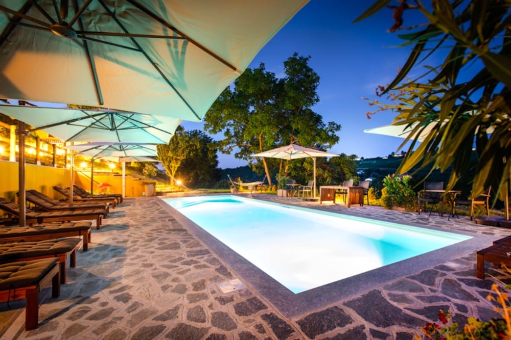 Svimmingpool på Villa Vinory La Mandragola med utsikt över Piemontes böljande vinlandskap, omgiven av vinrankor, grönska och lugna, exklusiva omgivningar