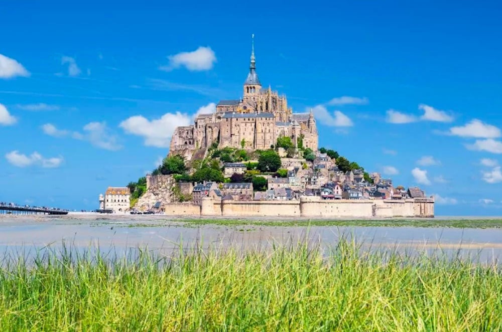 Mont-Saint-Michel vid lågvatten, med det majestätiska klostret som reser sig över sandbankarna i Normandie.