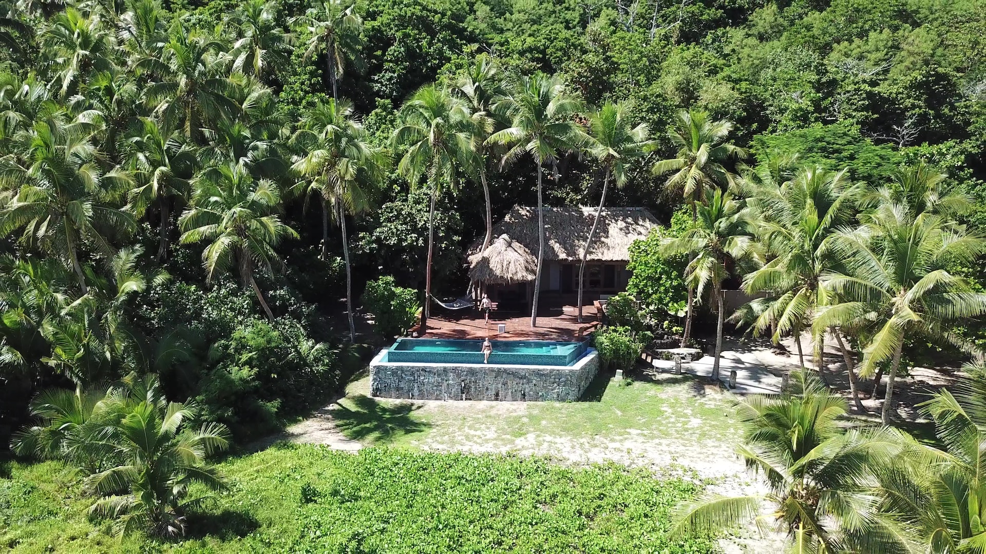 Pool mellan palmer på Yasawaöarna med utsikt över tropisk natur.