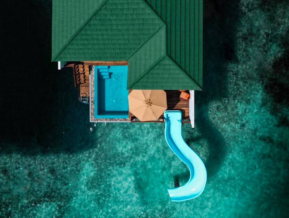 Foto ovanifrån av Siyam World Maldives med vattenvillor, turkost hav.