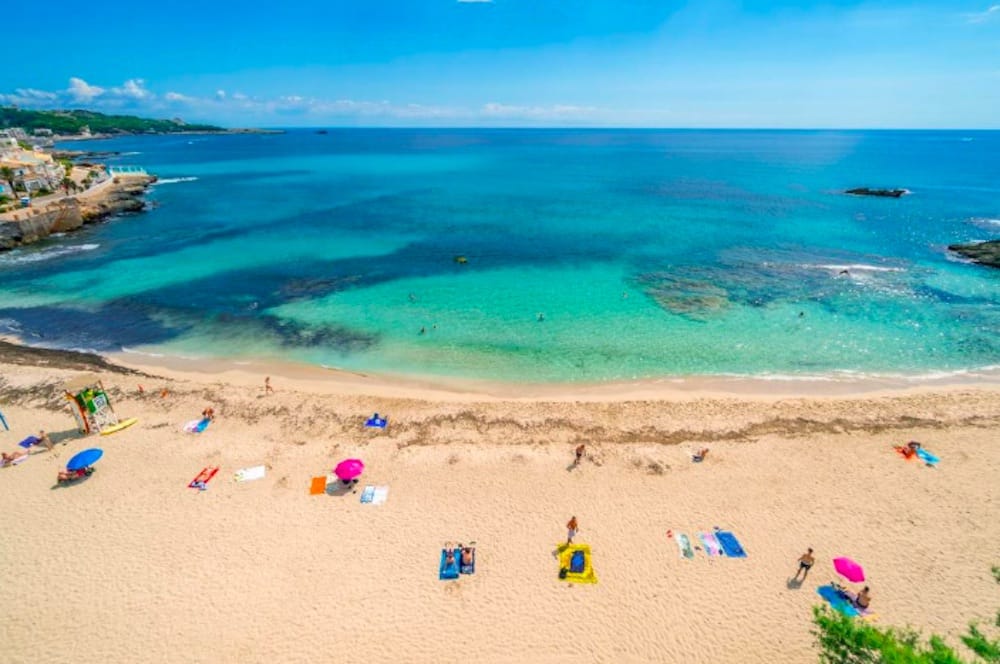Cala Ratjada med exklusiv fiskehamn och strand, kristallklart vatten, båtar vid kajen och en livfull men harmonisk atmosfär på Mallorca.