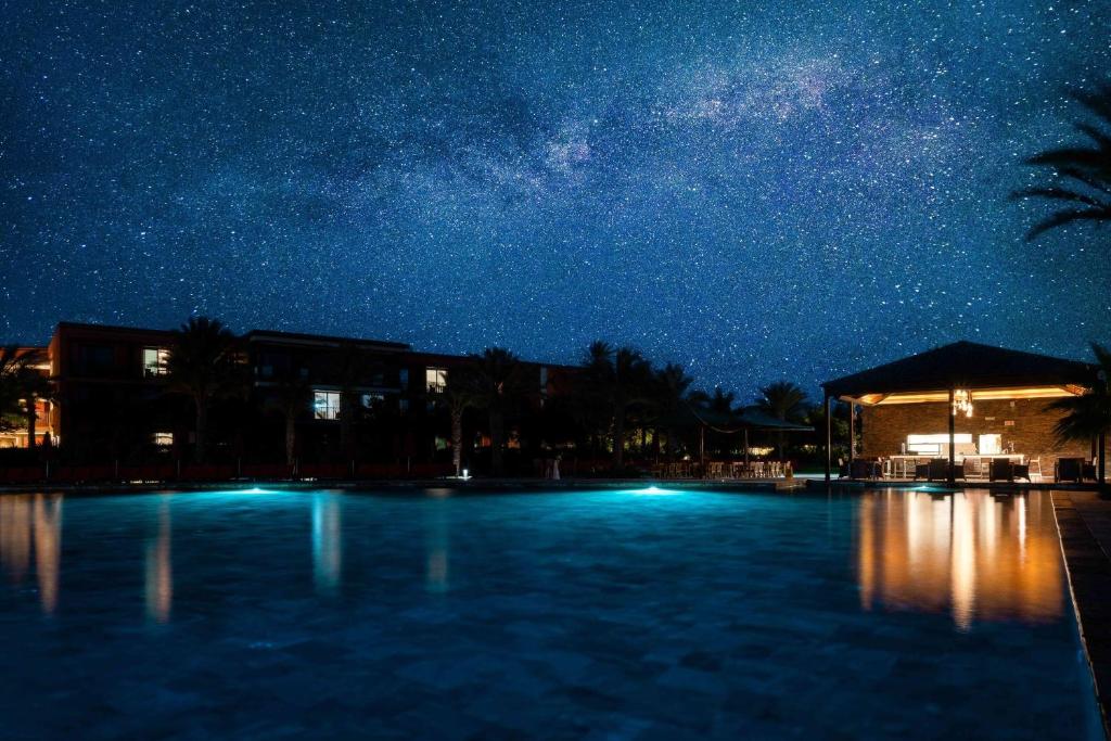 Opplyst infinity-basseng på Hilton Cabo Verde Sal Resort om kvelden, med stjernehimmel, palmer og eksklusiv resortstemning – luksuriøs ferieopplevelse på Sal i Kapp Verde.