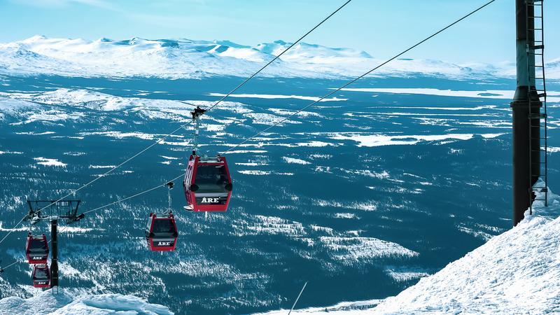 Vy över Åre med skidbackar, liftsystem och bykärna vid foten av fjället under vintersäsong.