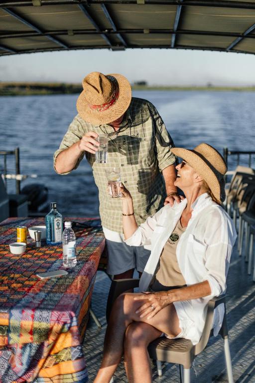 Ett par njuter av lunch ombord på safaribåten – en stillsam stund där flodens lugn och gemenskapen står i centrum, Serondela Lodge