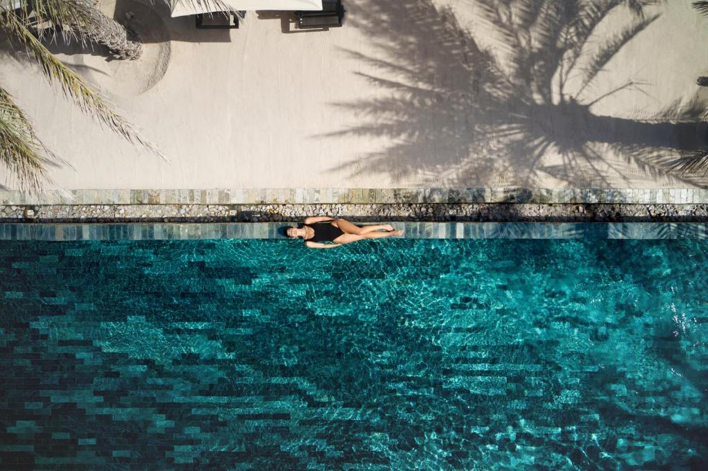 Total stillhet i turkist vann – der solens skyggespill, palmenes silhuetter og rolige svømmetak skaper en følelse av avkobling som varer lenge etter ferien.