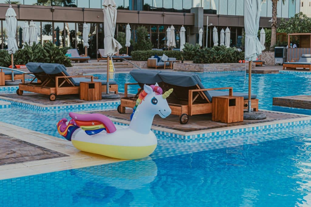 Barnvänligt poolområde på familjehotell i Spanien med lugna solbäddar och en uppblåsbar enhörning i poolen – en trygg och avslappnad semesterupplevelse för familjer som reser med små barn.