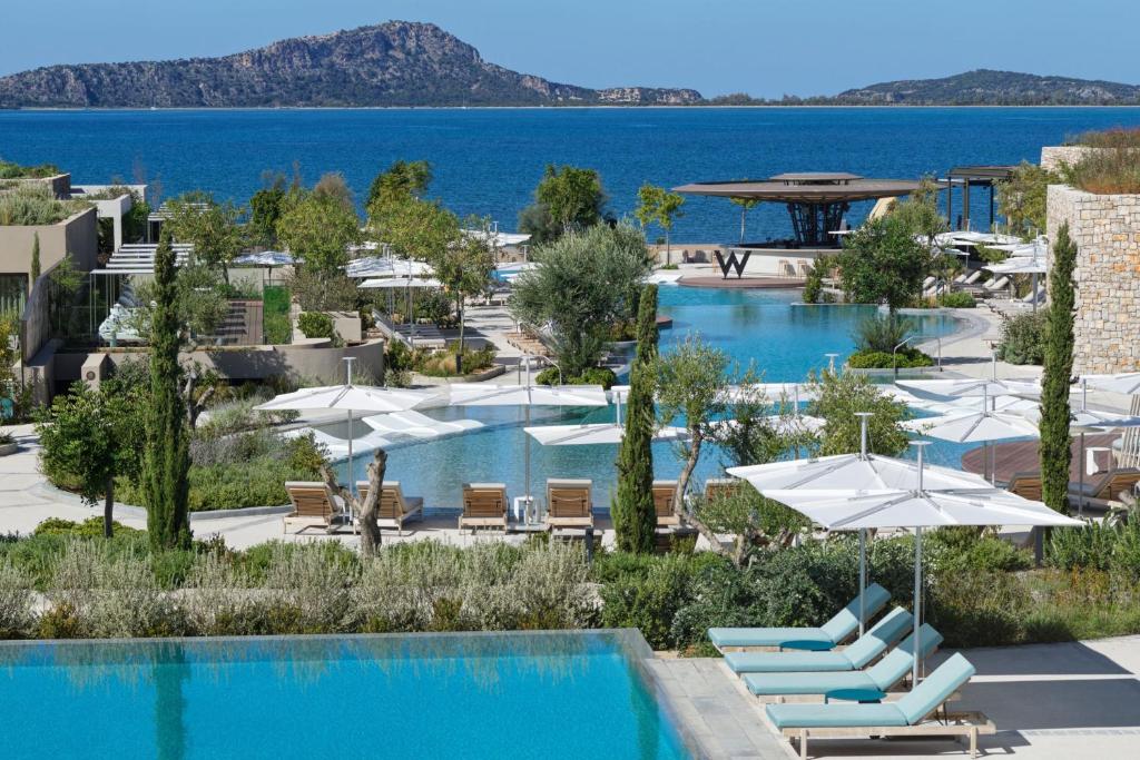 Poolområde med havsutsikt vid W Costa Navarino – modern lyxresort med infinitypooler, solstolar och stilren design i natursköna omgivningar vid Greklands kust.