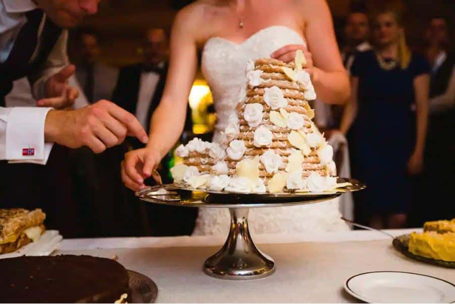 Brudpar som skär bröllopstårta i elegant miljö på Hankø Hotell & Spa