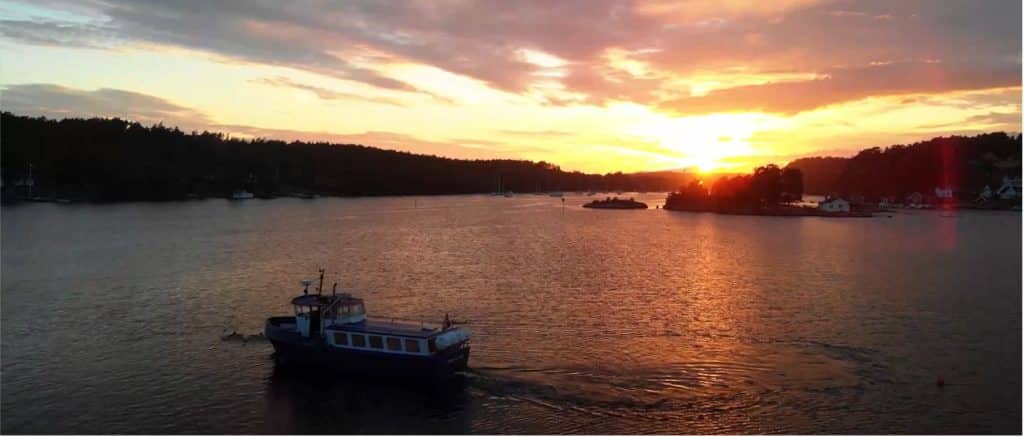 Färja i solnedgång över skärgården vid Hankø med stilla vatten och gyllene himmel