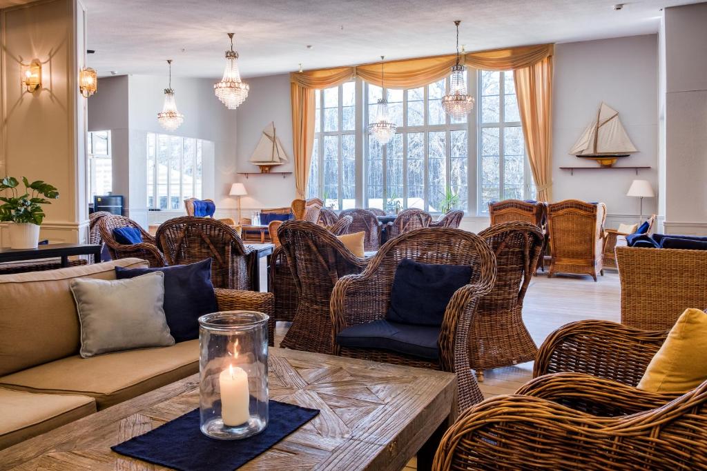 Inbjudande loungeområde på Hankø Hotell & Spa med rottingmöbler, kristallkronor och stora fönster mot naturen