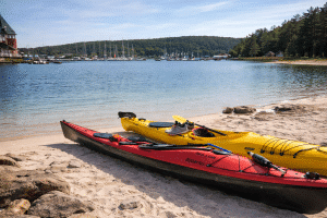 Kajaker på sandstrand vid lugnt vatten i skärgården på Hankø