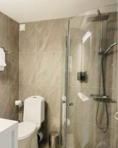 Modernt badrum med dusch, glasvägg och stilrena detaljer på Hankø Hotell